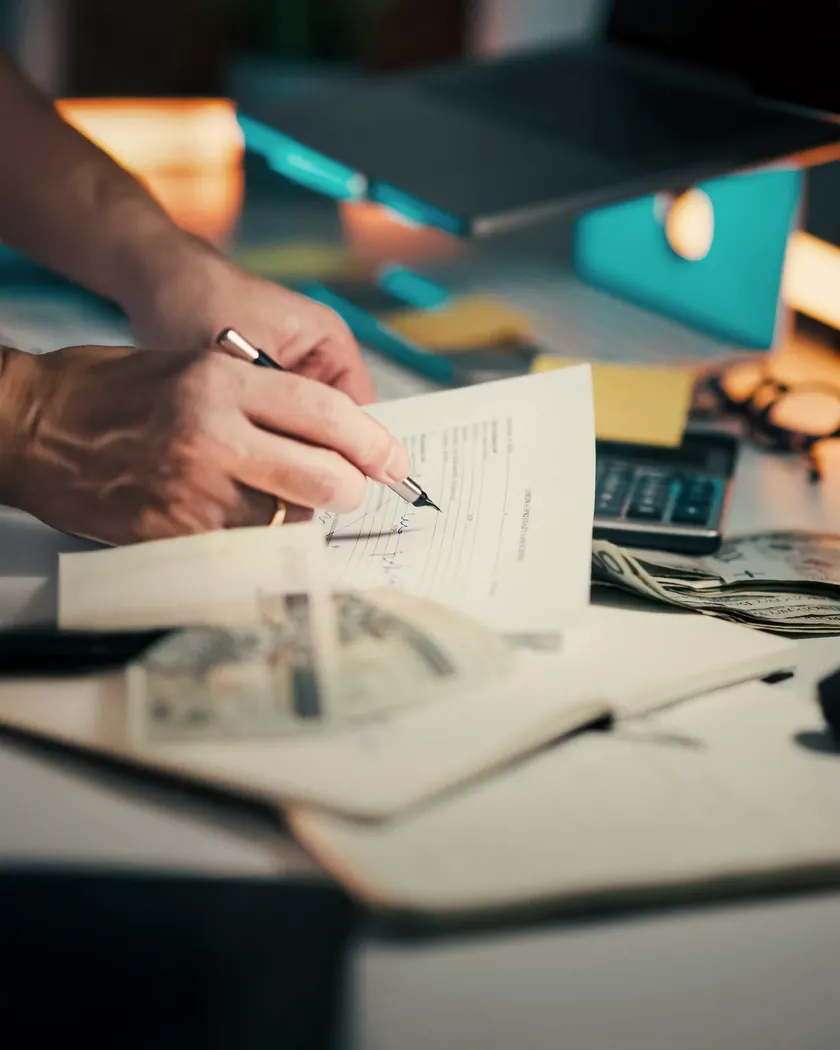 A person reviewing and signing paperwork at a desk